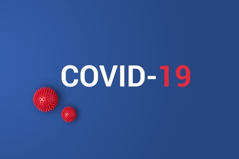 Text COVID-19 on a blue background, with COVID- in white and 19 in red. Two red spiky spheres resembling virus particles appear on the left side of the image.